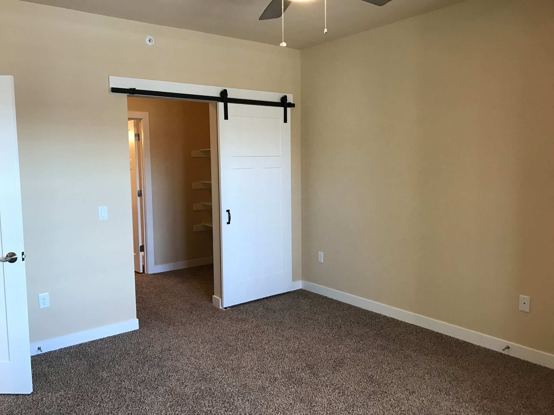 a bedroom with a sliding barn door and a ceiling fan
