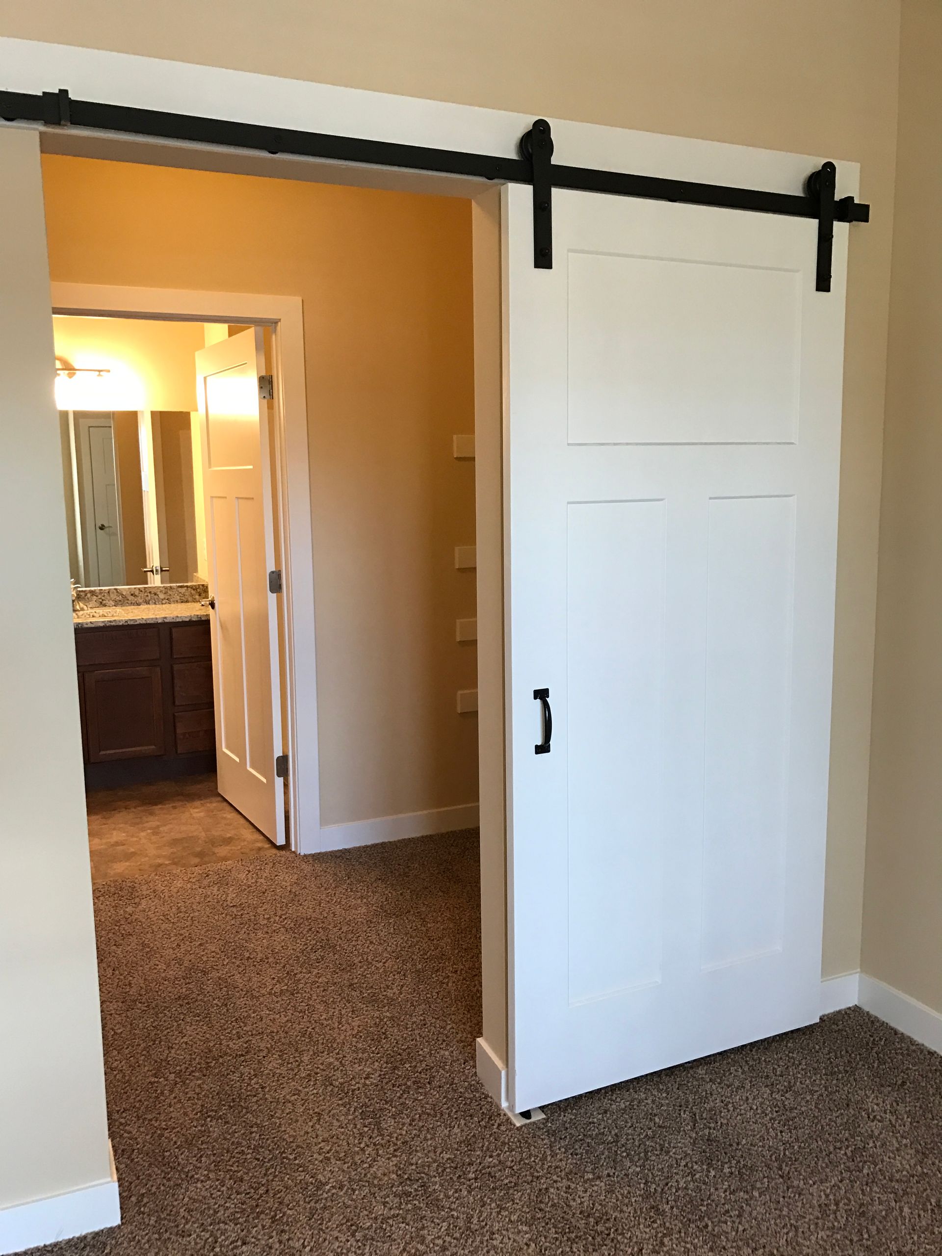 a bedroom with a sliding barn door leading to a bathroom