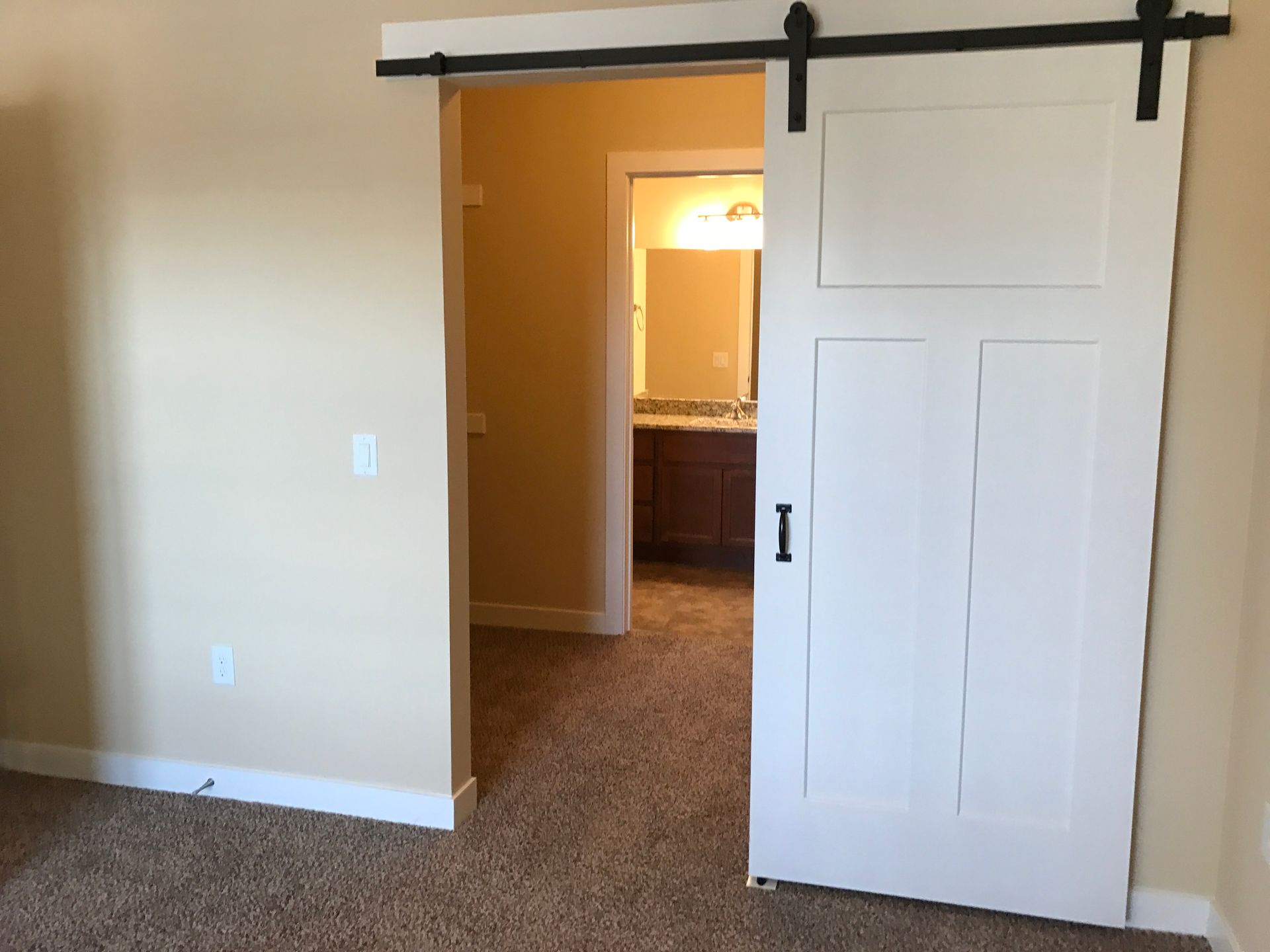 a bedroom with a sliding barn door leading to a bathroom