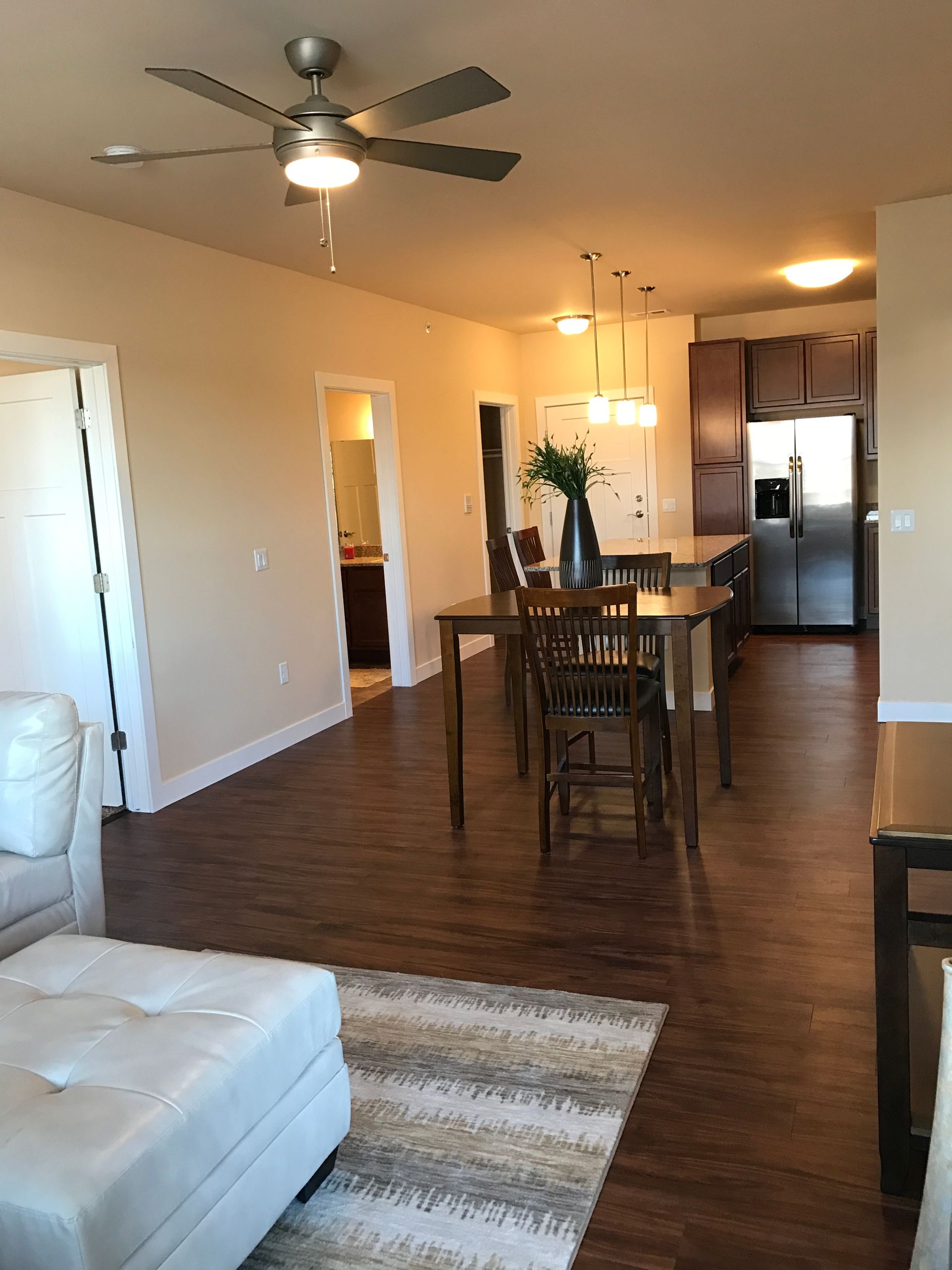 a living room with a table and chairs and a ceiling fan