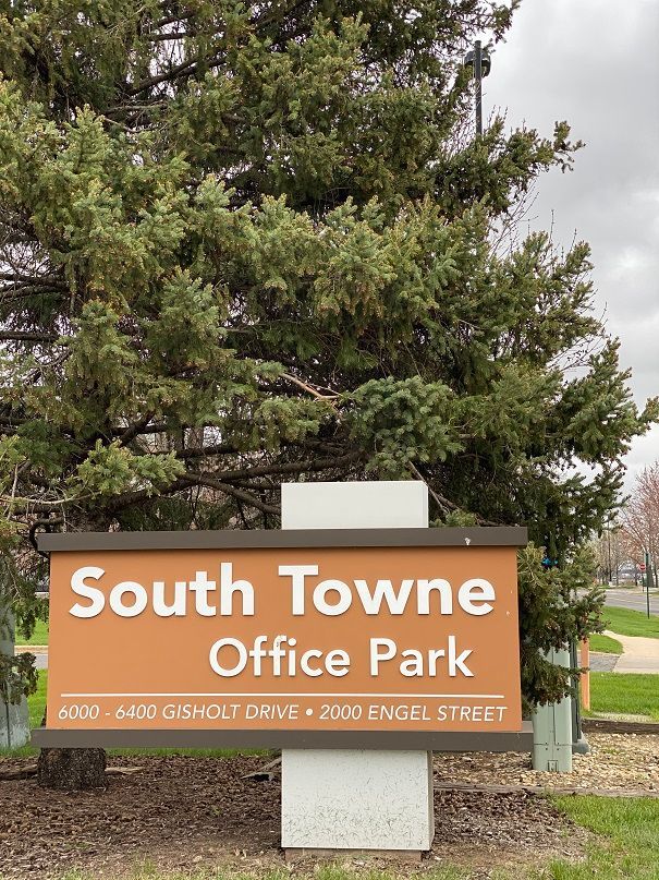 a sign for south towne office park sits in front of a tree