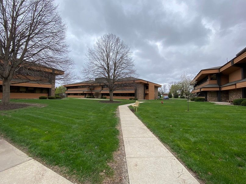 a walkway leading to a large building with a lush green lawn
