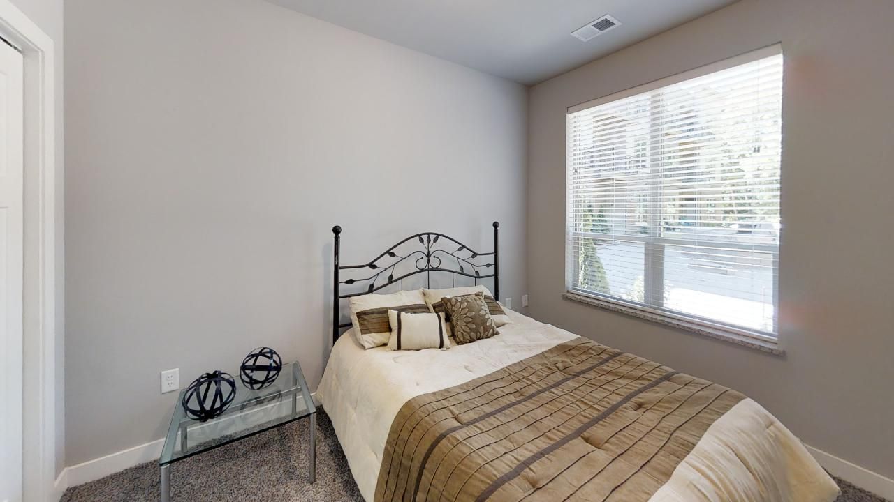 a bedroom with a bed and a window with blinds