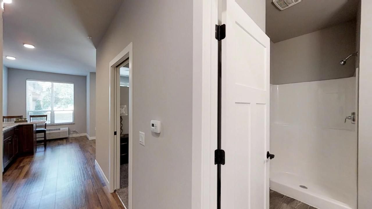 a hallway leading to a bathroom with a walk in shower