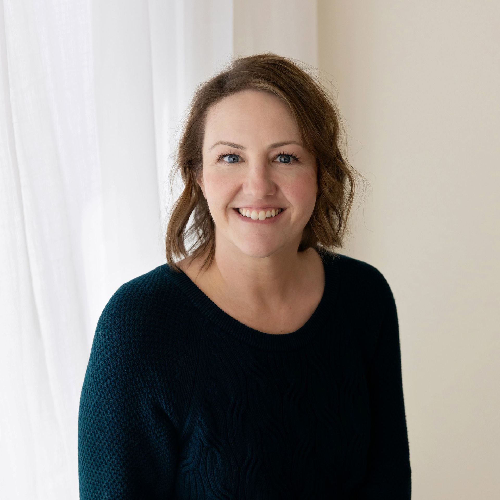 a woman in a blue sweater smiles for the camera