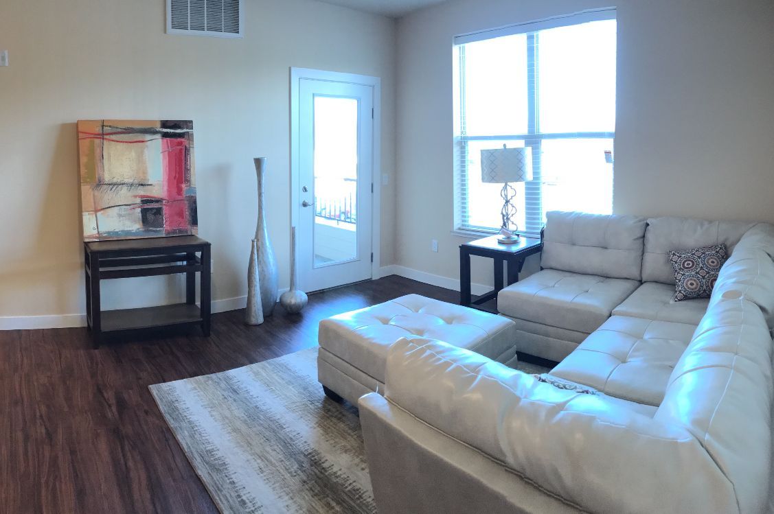 a living room with a white couch and ottoman
