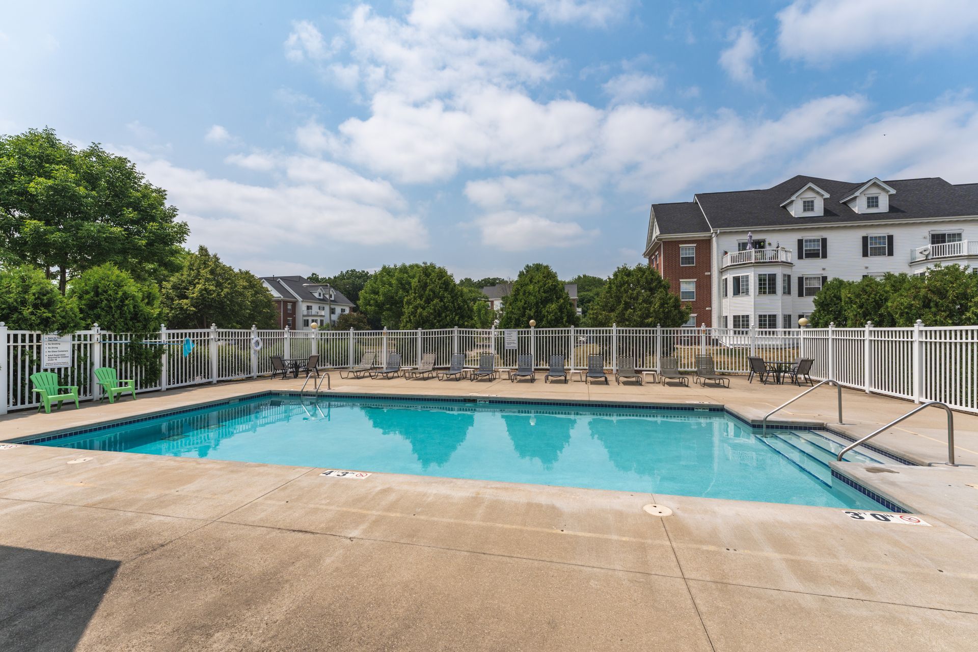 a large swimming pool is surrounded by chairs and a white fence