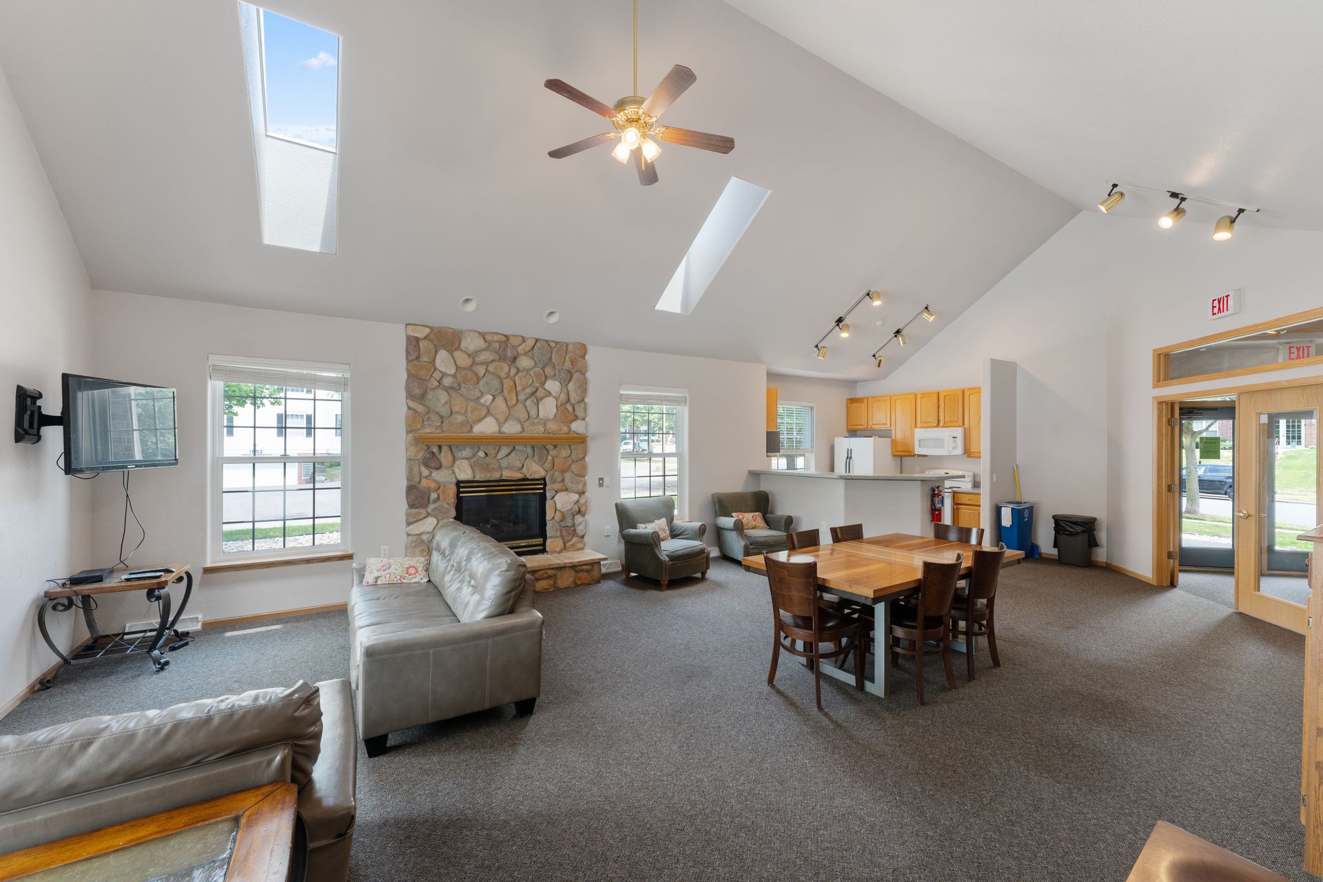 a living room with a stone fireplace and a ceiling fan