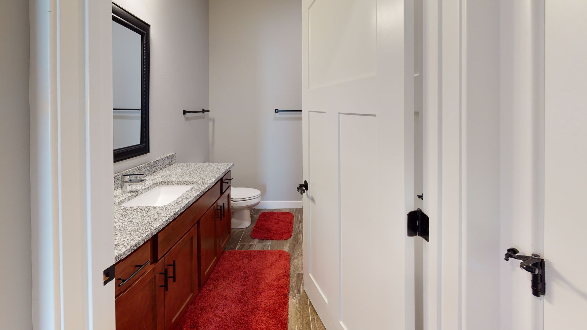 a bathroom with a sink toilet and red rug