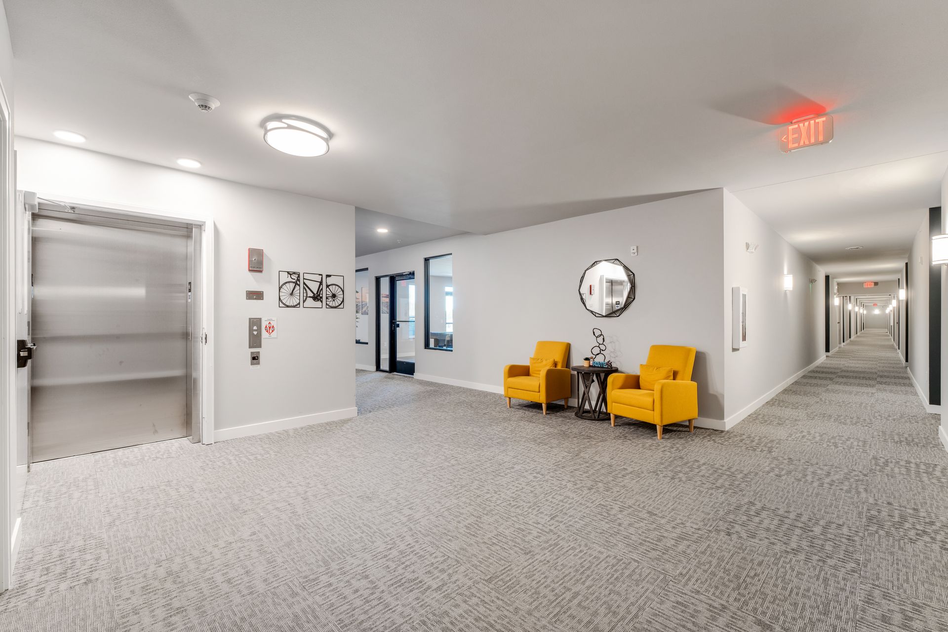 a hallway with a red exit sign on the ceiling