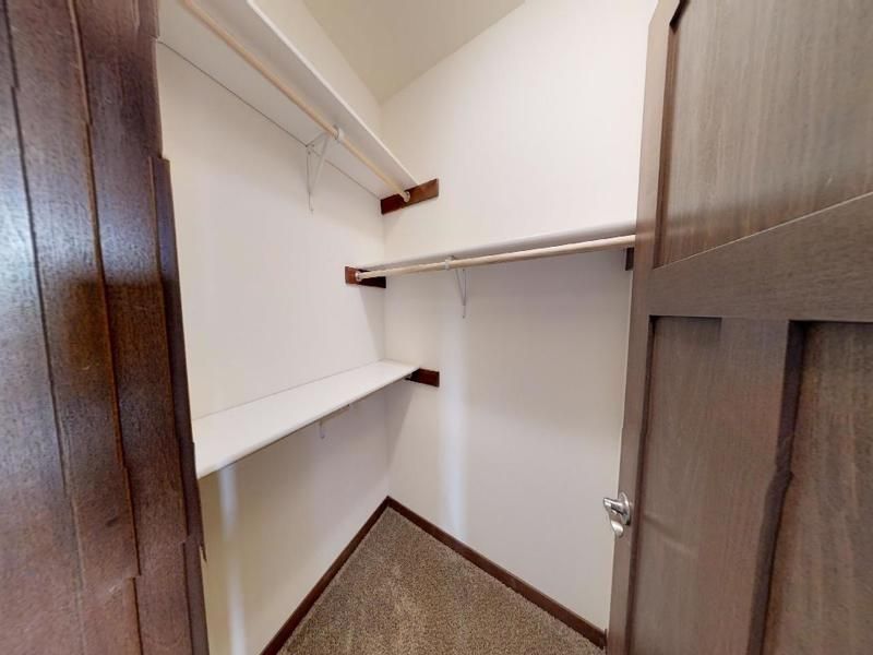 a walk in closet with a wooden door and shelves