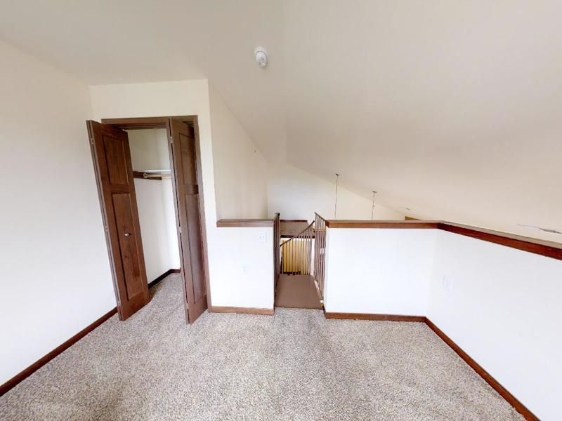 an empty room with a staircase and a closet .