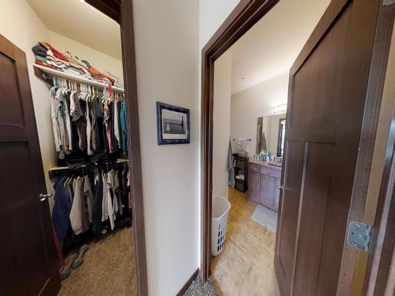 a walk in closet leading to a bathroom with a picture on the wall