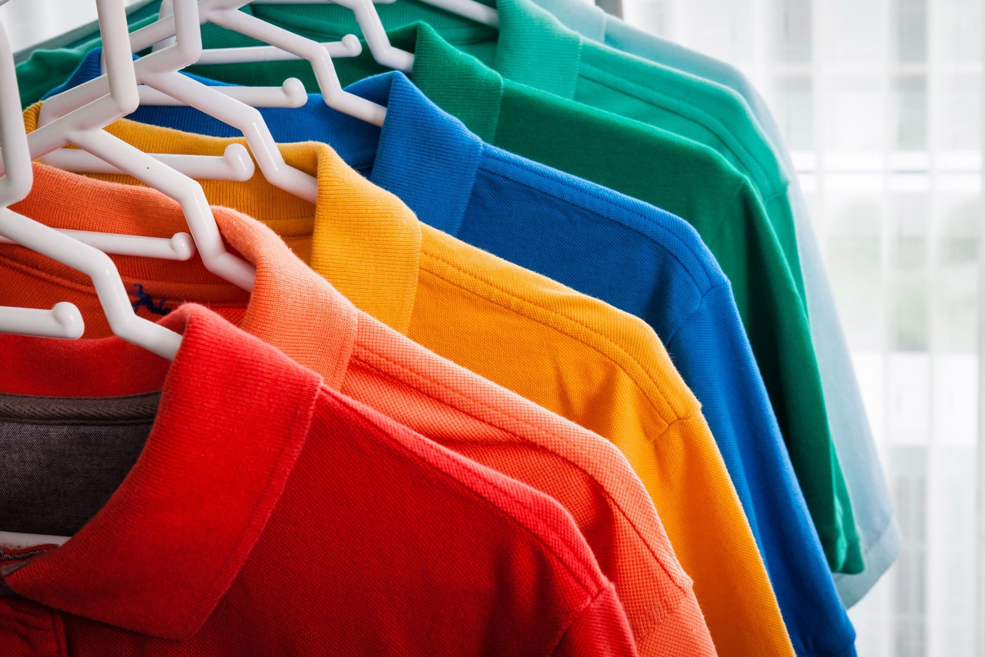 Gradient of colorful polo shirts on hangers