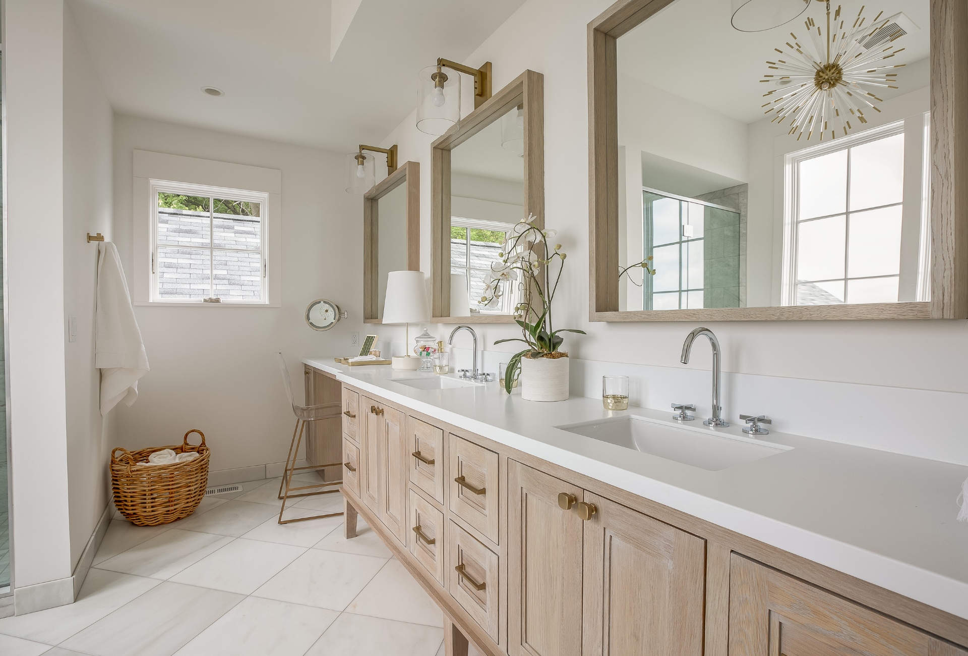 Elegant white bathroom with double vanity, large mirrors, light wood cabinets, and marble flooring.