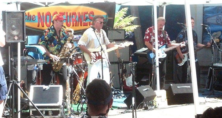 A group of men playing instruments in front of a sign that says the nocturnes