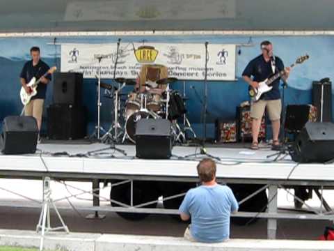 A man sits on a bench watching a band on stage