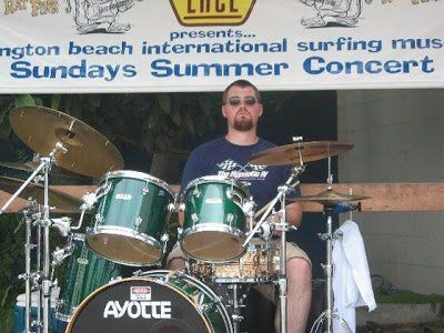 A man playing drums in front of a banner that says sundays summer concert