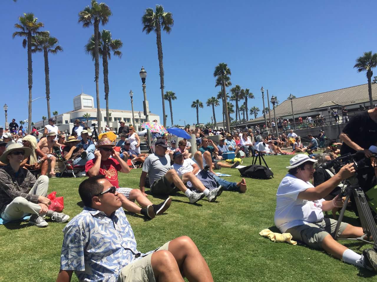 A group of people are sitting on the grass in a park