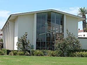 Main Street Library White building with large glass windows, green lawn and bushes.