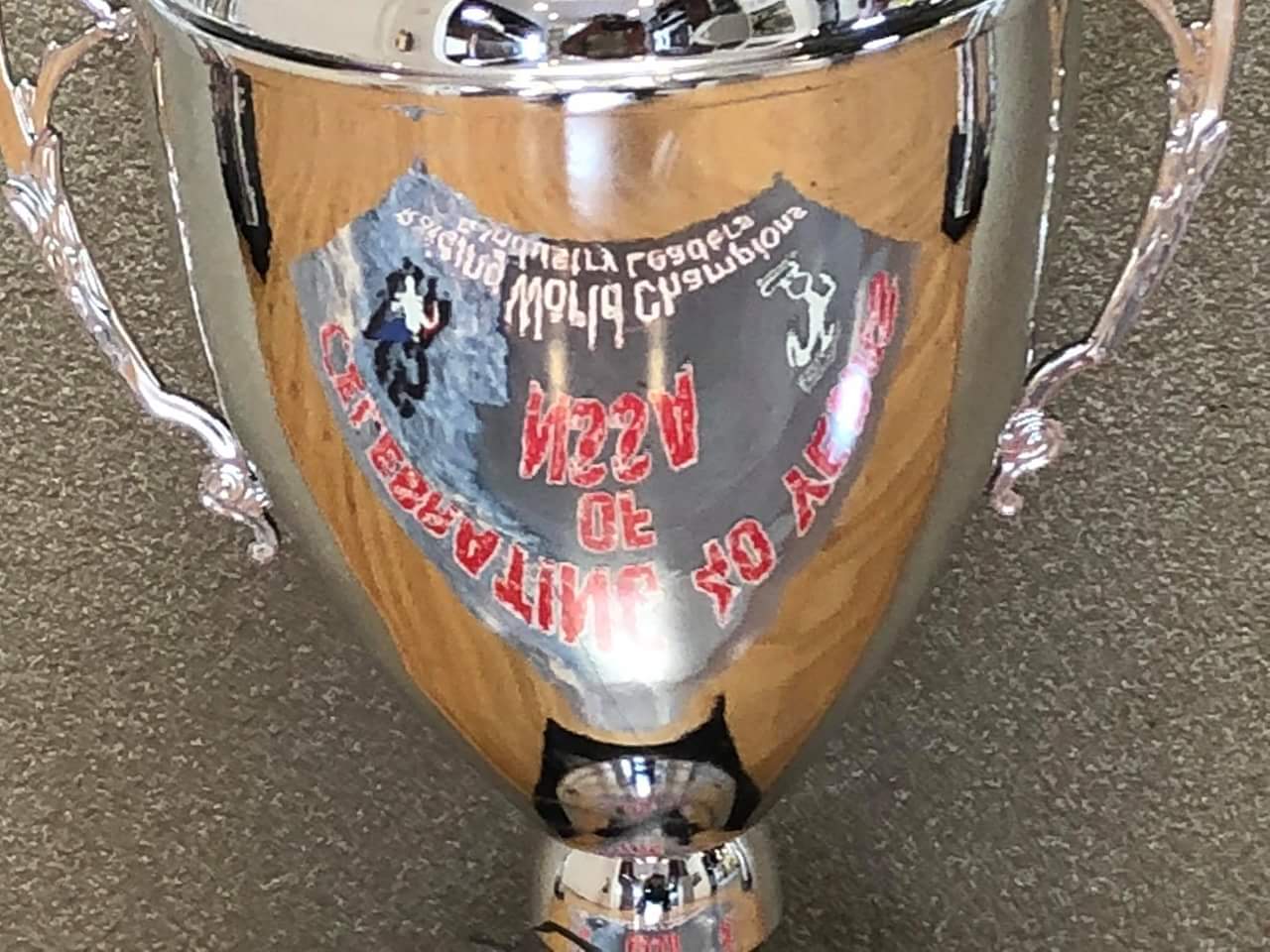 A silver trophy is sitting on a wooden table.