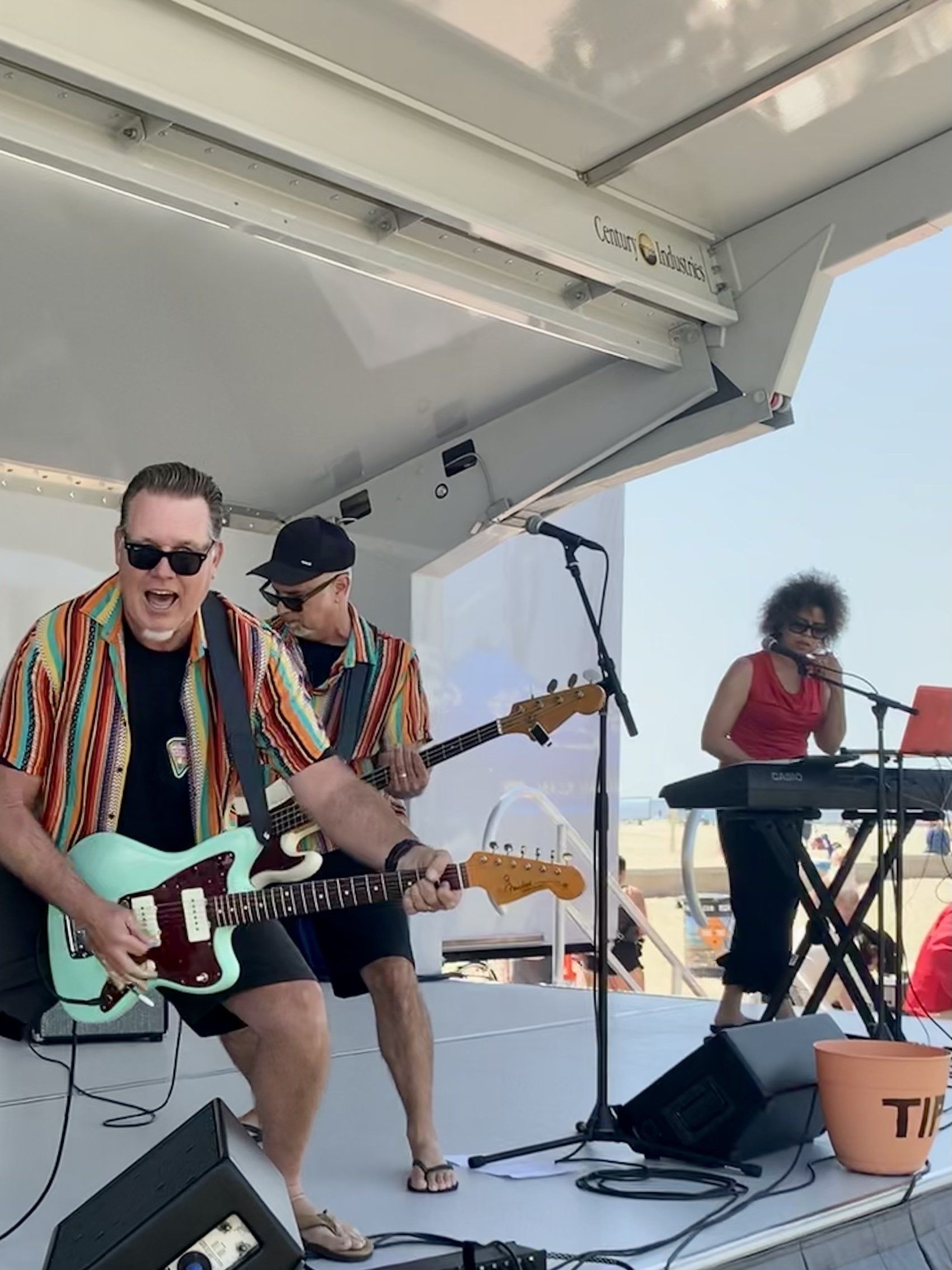 A man playing a guitar on a stage with a woman playing a keyboard in the background
