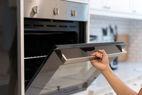 Hands Open the Oven in the Kitchen — Kansas City, MO — At Your Service Appliance Repair