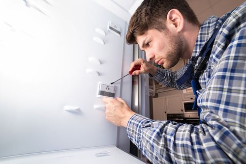 Male Worker Repairing Refrigerator — Kansas City, MO — At Your Service Appliance Repair