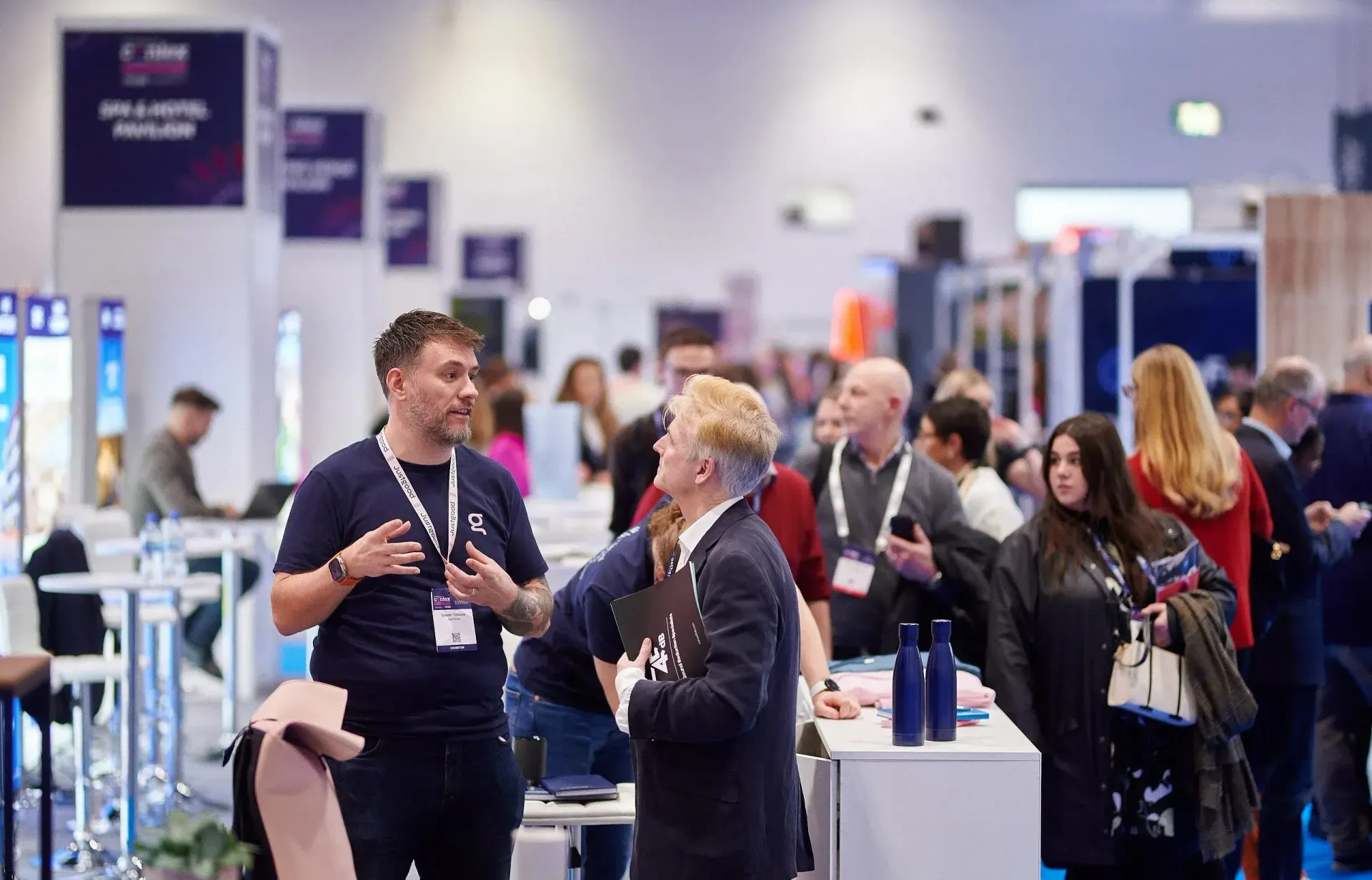 A group of people are standing in a room talking to each other.