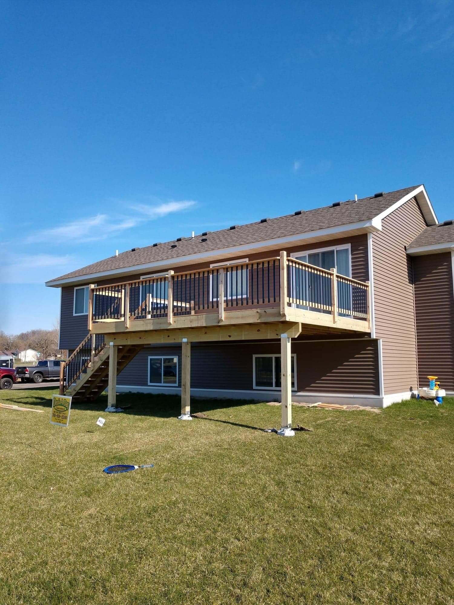Finished wooden deck with stairs behind brown home