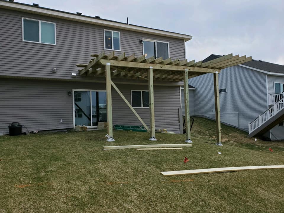 Finished wooden pergola attached to brown home