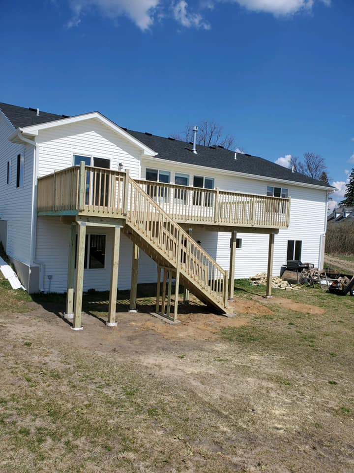 Finished wooden deck with stairs behind white home