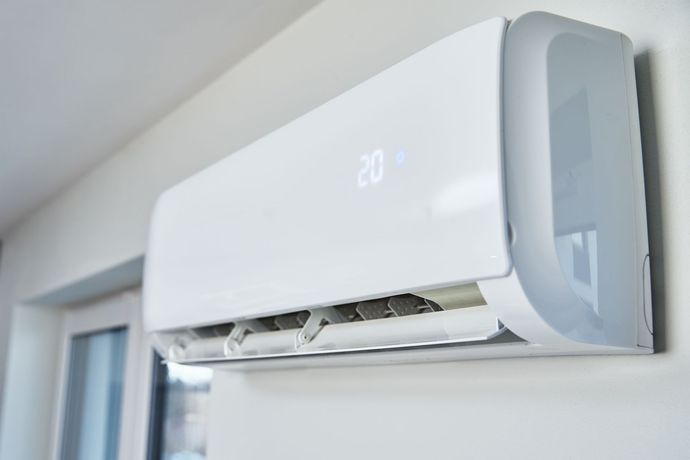 White wall-mounted air conditioning unit with digital temperature display.