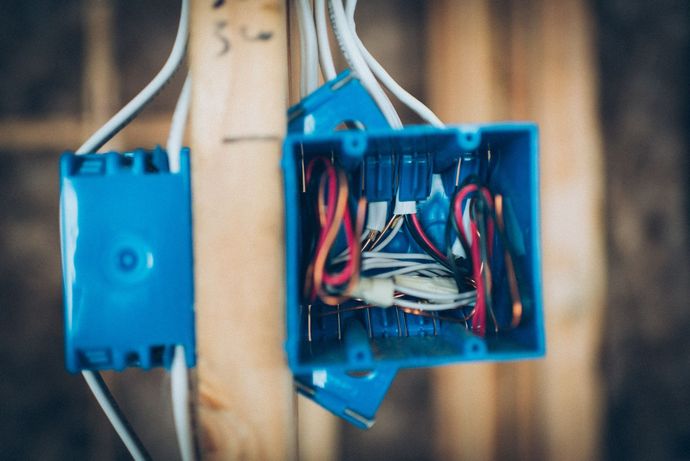 Blue electrical boxes with wires on wooden studs.