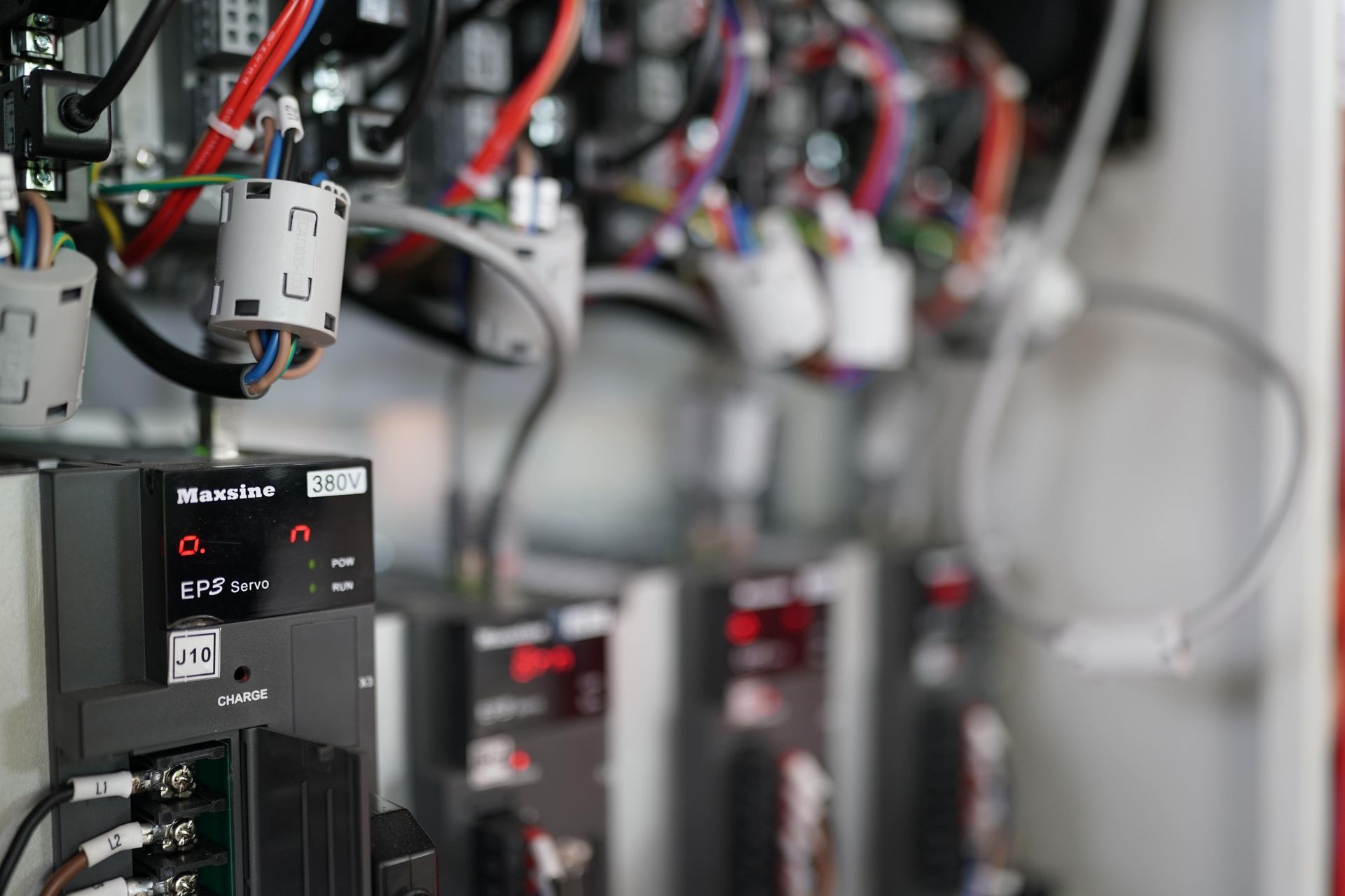 Close-up of electrical components and wiring inside a control panel, with red and white wires visible.