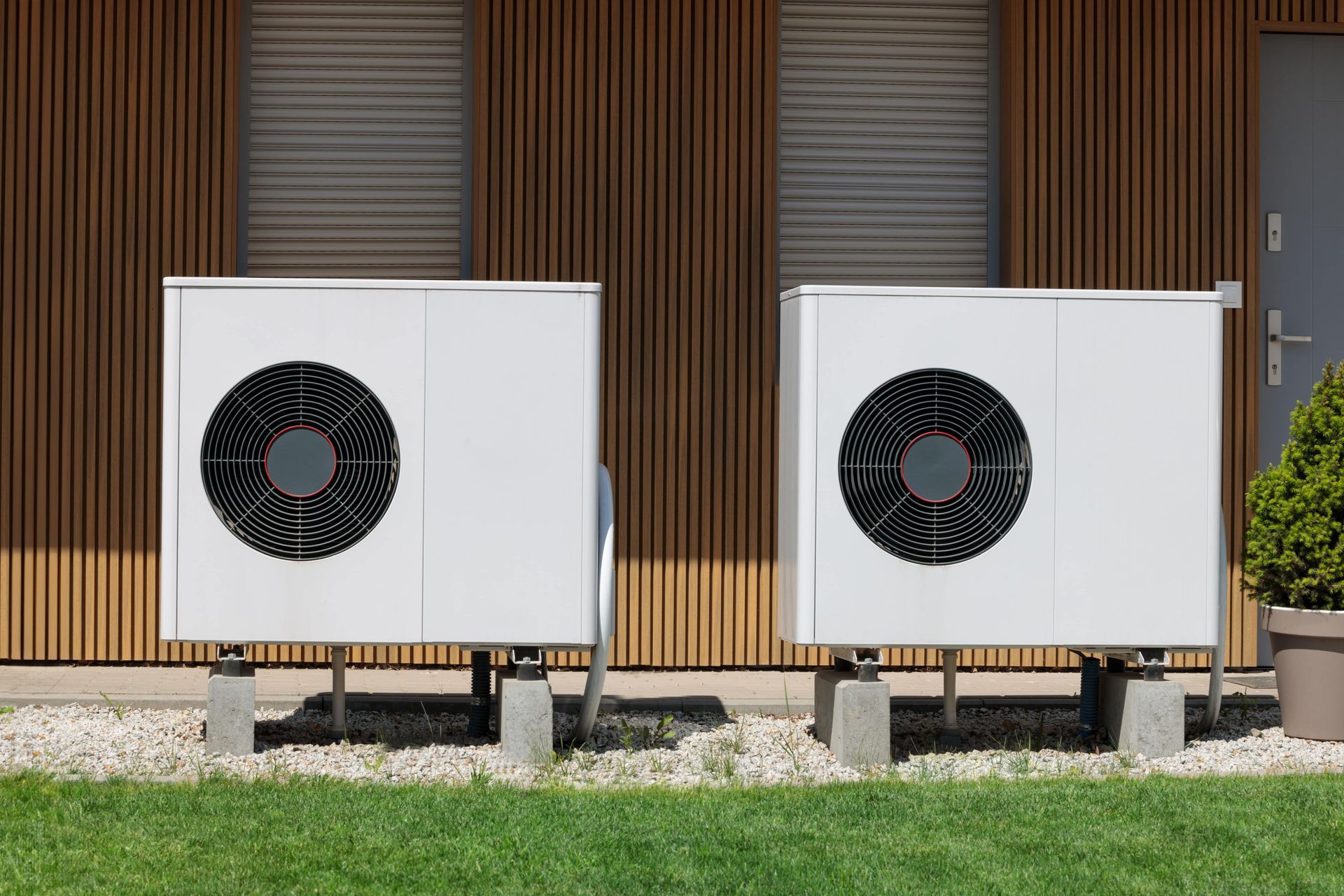 Snow-covered air conditioning units on a rooftop with a wooden balcony and a frosted window.