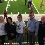A group of people are posing for a picture in front of a football field.
