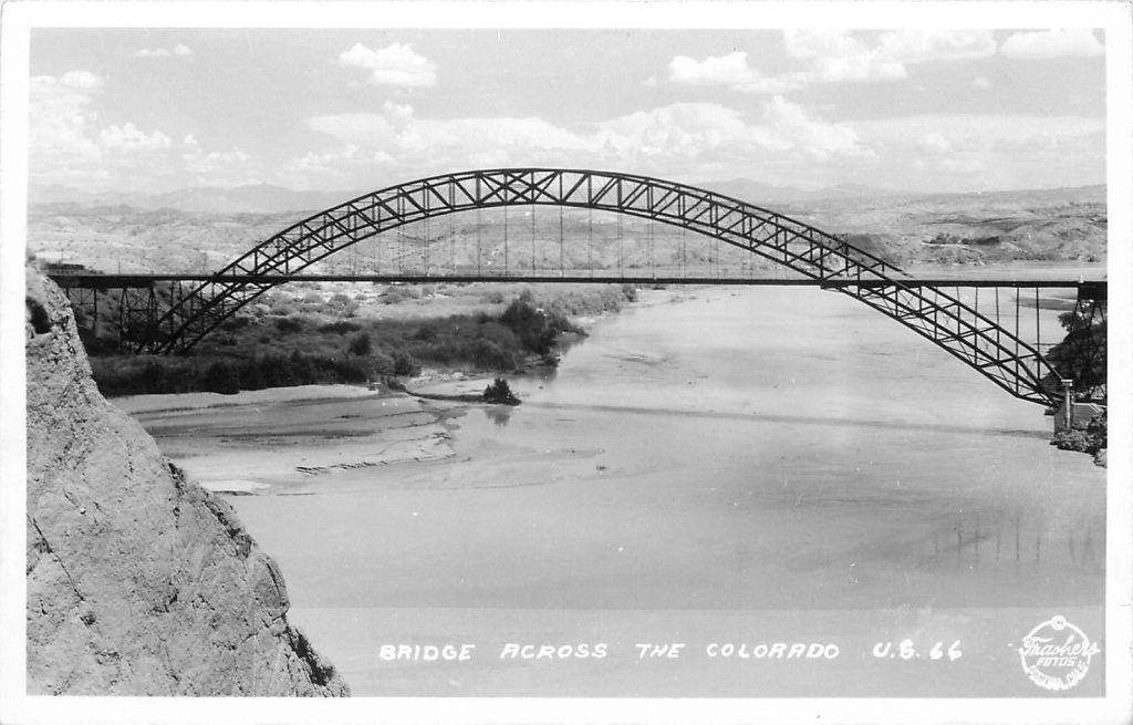 A black and white photo of a bridge over a river.