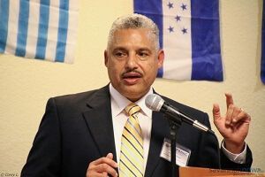 A man in a suit and tie is speaking into a microphone.