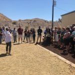 A group of people are standing on top of a dirt field.