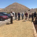 A group of people are standing in a parking lot in front of a mountain.