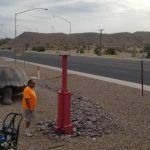 A man is standing next to a red pole on the side of the road.