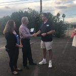 A group of people are shaking hands in a parking lot.