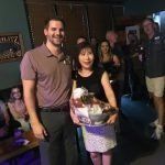 A man and a woman are standing next to each other in a room holding a bucket of food.