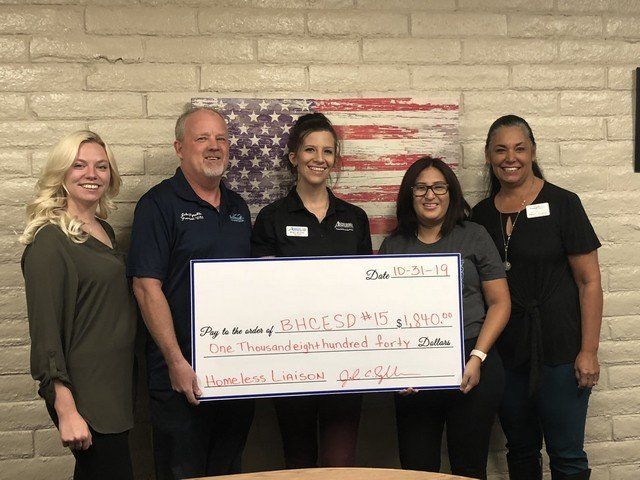 A group of people holding a large check in front of an american flag.