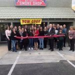 A group of people are standing in front of a smoke shop.