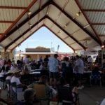 A large group of people are sitting at tables under a tent.