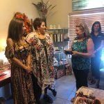 A group of women are standing in a living room talking to each other.