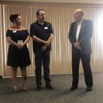 Three people are standing next to each other in a room.
