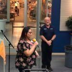A woman is singing into a microphone while a man stands behind her.